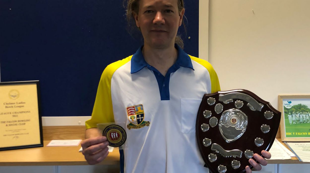 Karl Bunyan holding his Essex indoor county badge and the Unbadged Singles trophy